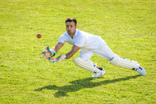 Young male wicketkeeper catching the ball on the field